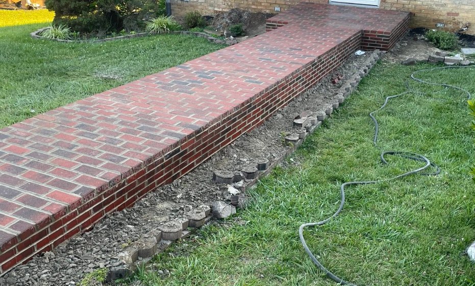 Brick walkway running to a house and turning into entry steps