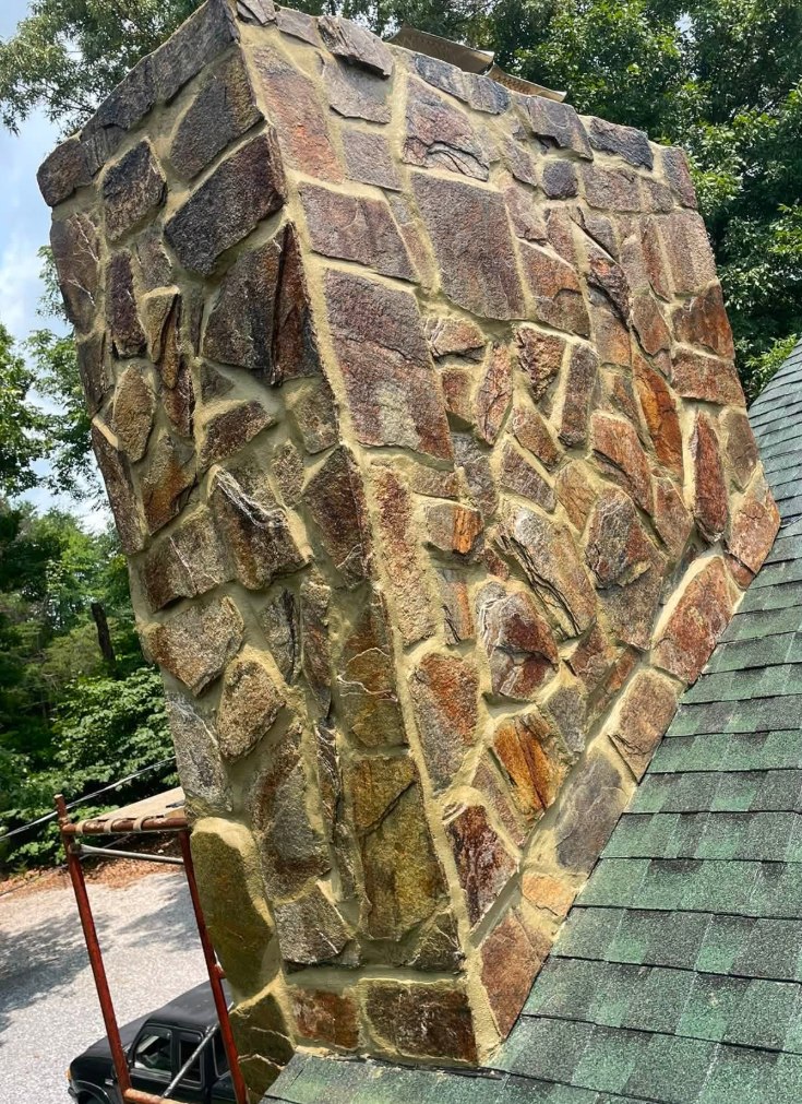 Stone chimney after repointing, joints filled with warm buff mortar