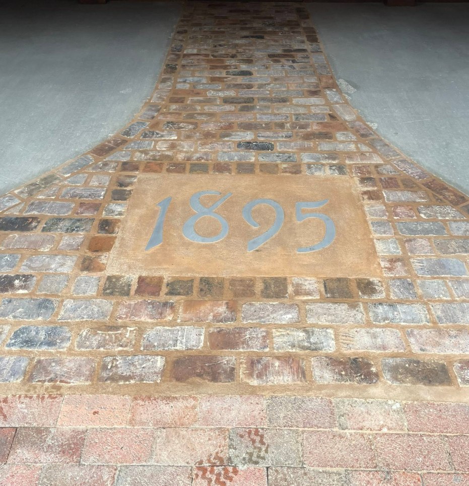 Salvaged brick walkway with an 1895 date stone set into the centre