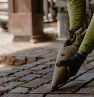 Gloved hand setting hand-molded 1800s brick with a trowel