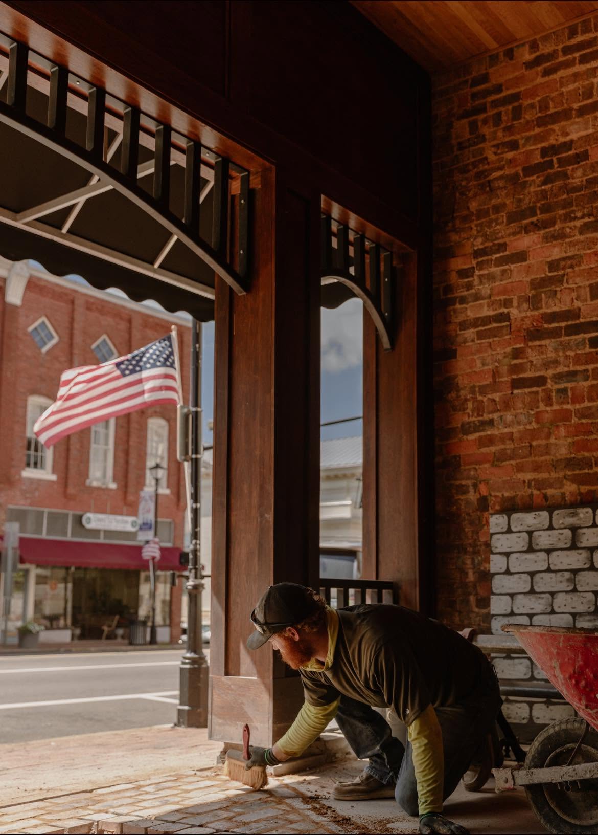 Jordan Fillers brushing in a brick sidewalk under a downtown storefront awning