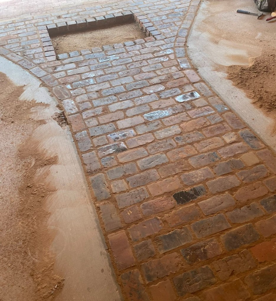 Floor of reclaimed brick with a framed hearth opening